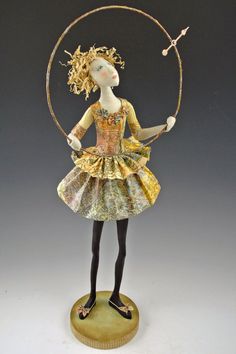 a figurine is standing on a base with a hoop around her neck and hands in the air