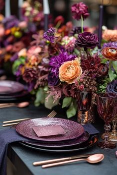 the table is set with purple and orange plates, silverware, and floral centerpieces