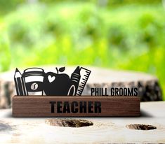 a wooden sign that says teacher with an apple and pencils on top of it