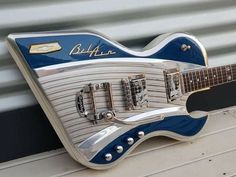 a blue and white electric guitar sitting on top of a table next to a wall