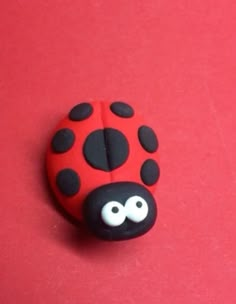 a red and black ladybug brooch sitting on top of a pink surface