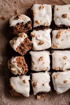 a bunch of brownies with white frosting and nuts on top are arranged in a rectangle