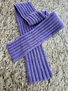 a purple knitted scarf laying on top of a counter