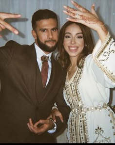 a man and woman are posing for a photo in front of a curtain with their hands up