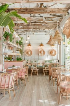 the inside of a restaurant with wooden tables and chairs, hanging plants and potted plants