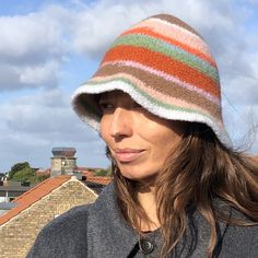 a woman wearing a multicolored knitted hat on top of her head with buildings in the background