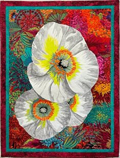 two white flowers are in the middle of a colorful quilted artwork piece with red, yellow and green accents