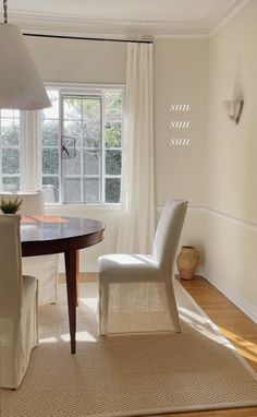 a dining room table with two chairs and a lamp on top of it in front of a window