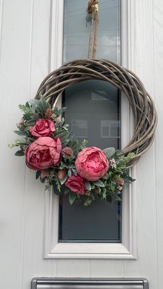 a wreath with pink flowers hanging on the front door