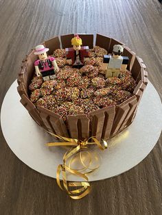 a chocolate cake with sprinkles and mini people on top is sitting on a white plate