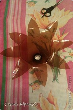 a pair of scissors sitting on top of a pink and white table cloth with flowers