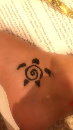 a small tattoo on the foot of a person with a turtle in it's center