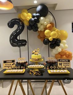 a table topped with lots of desserts and balloons in the shape of number two