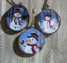 three snowman ornaments hanging from strings on a wooden surface