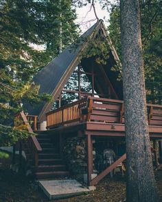 a cabin in the woods with stairs leading up to it's second floor and upper level