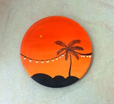 an orange and black plate with a palm tree painted on the front in white lights