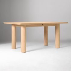 a wooden table sitting on top of a white floor next to a gray wall in an empty room