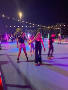 two girls on roller skates holding hands in the middle of an ice rink at night