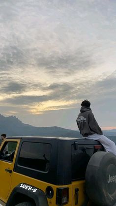 a man sitting on the back of a yellow jeep with an inflatable tire