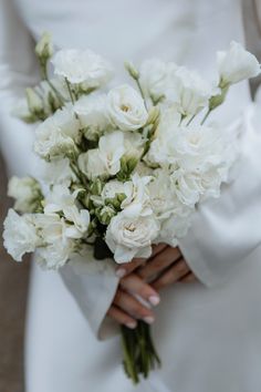 a bride holding a bouquet of white flowers