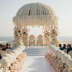 an outdoor ceremony setup with white flowers and pink peonies on the aisle, overlooking the ocean