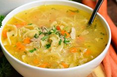 a bowl of chicken noodle soup with carrots and parsley on the side