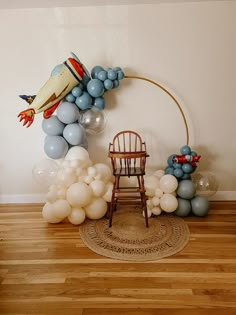 balloon arch and chair in front of wall decorated with blue and white balloons on wooden floor