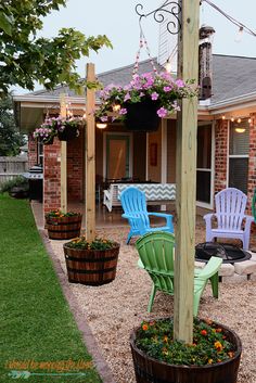 some chairs are sitting on the gravel in front of a house with lights and flowers