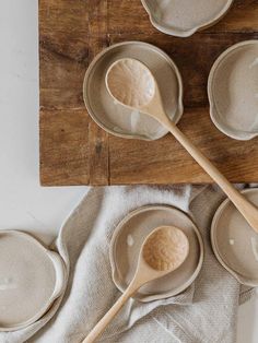 four bowls and two spoons on a wooden table