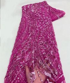 a woman's hand is holding the bottom of a pink dress with sequins on it