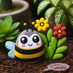 a toy bee sitting in the dirt next to some flowers