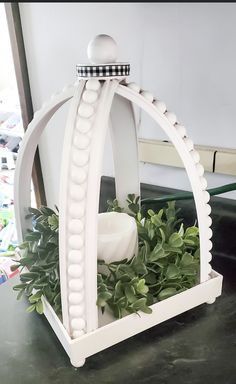 a white candle holder sitting on top of a table next to a green plant and mirror