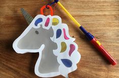 a paper unicorn ornament next to a crayon marker on a wooden table