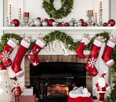 a fireplace decorated for christmas with stockings and decorations