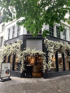 a store front with white flowers on the outside