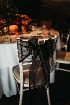 a chair with a black bow tied to it's back sitting in front of a table