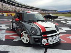 two cars on a race track, one is white and the other is grey with red stripes