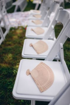 rows of white folding chairs with hats on them are set up for an outdoor ceremony