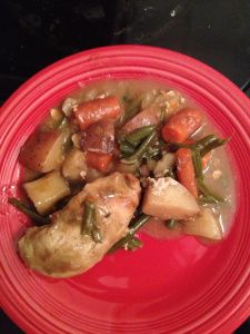 a red plate topped with meat and veggies covered in gravy on top of a stove