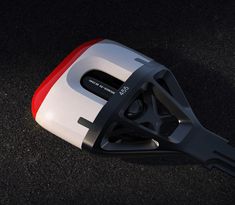 a close up of a black, white and red object on the ground with dark background