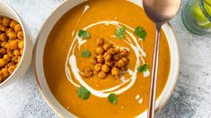 two bowls filled with soup and garnished with chickpeas on the side