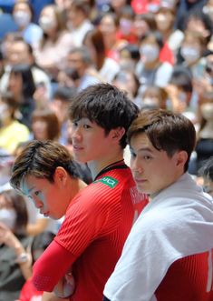 three young men standing next to each other in front of a crowd