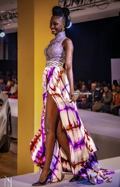 a woman is walking down the runway wearing a dress with purple and red tie dye