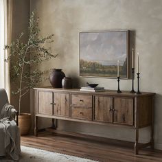 a living room with a couch, table and vases on the sideboard in front of a window