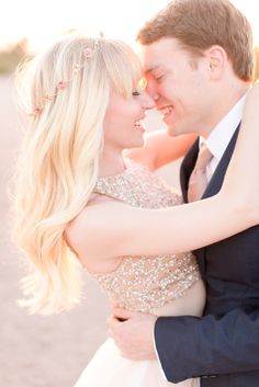 a bride and groom embracing each other on the beach