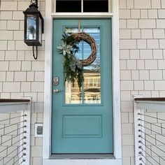 a blue front door with two wreaths on it and a light hanging from the side