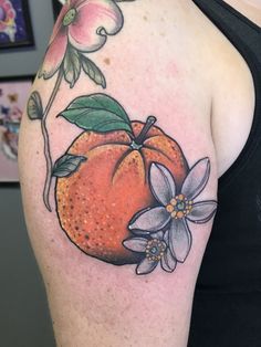 an orange with flowers and leaves on the arm is shown in this tattoo style photo