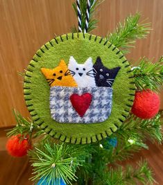 a christmas ornament with three cats in a cup