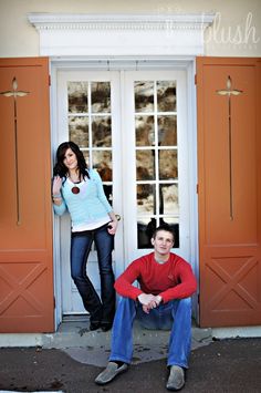 a man and woman posing for a photo in front of an orange door with shutters