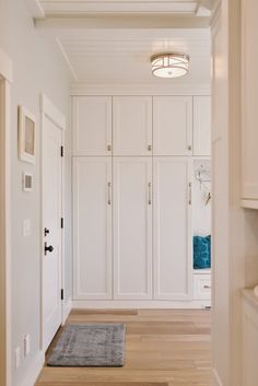 an empty hallway with white cabinets and wood floors